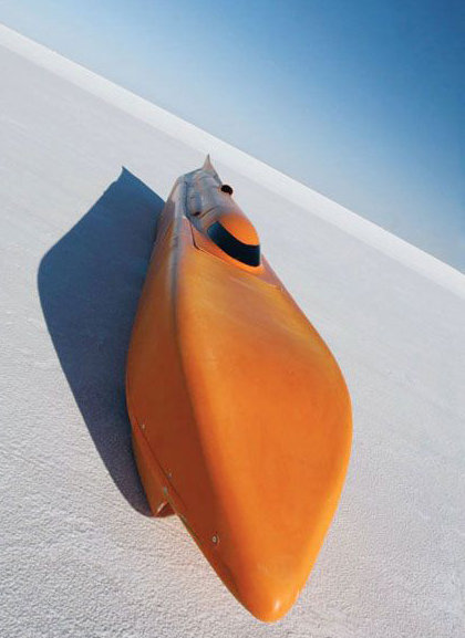 Orange kayak on a flat white salt flat under a clear blue sky.